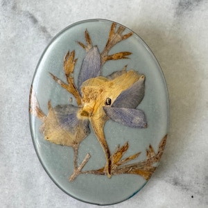 1980s Vintage Oval Resin Brooch – Pressed Yellow & Purple Flowers in Pale Blue Resin – 4.9 cm x 3.9 cm (1.93 in x 1.54 in)